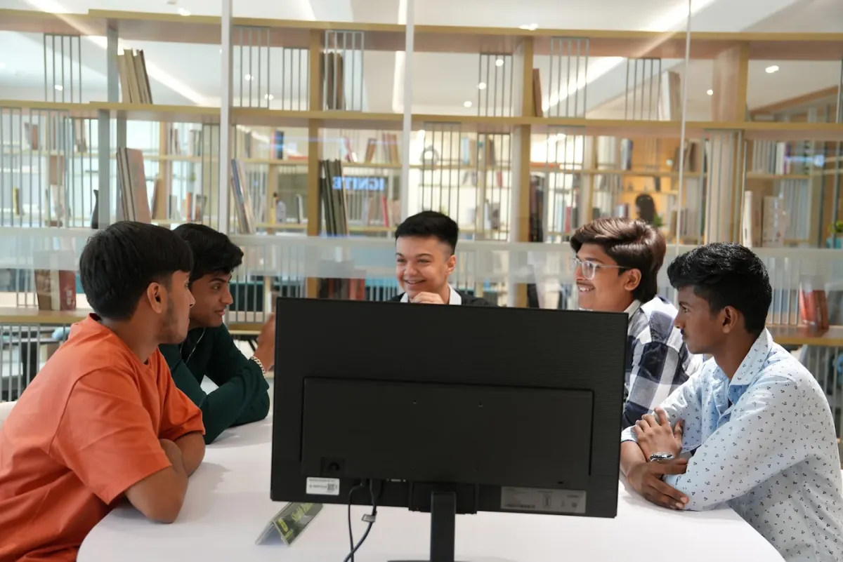 Students collaborating around a computer during a practical learning session